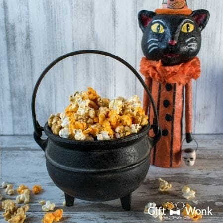 A witch cauldron filled with candied popcorn and a Halloween cat statue 